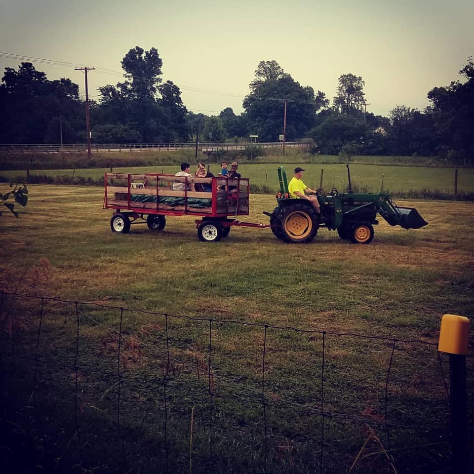 tractor pulling hay wagon with people in it