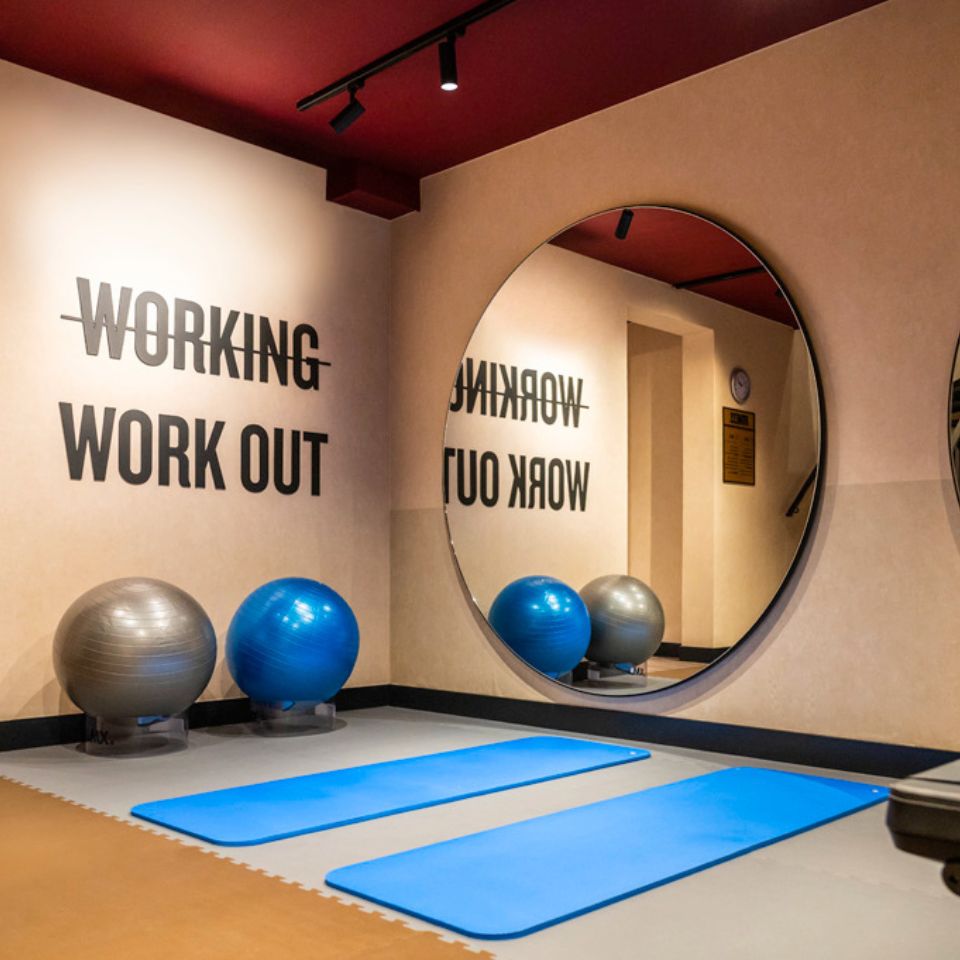 A room with a large mirror, yoga mats and excercise balls
