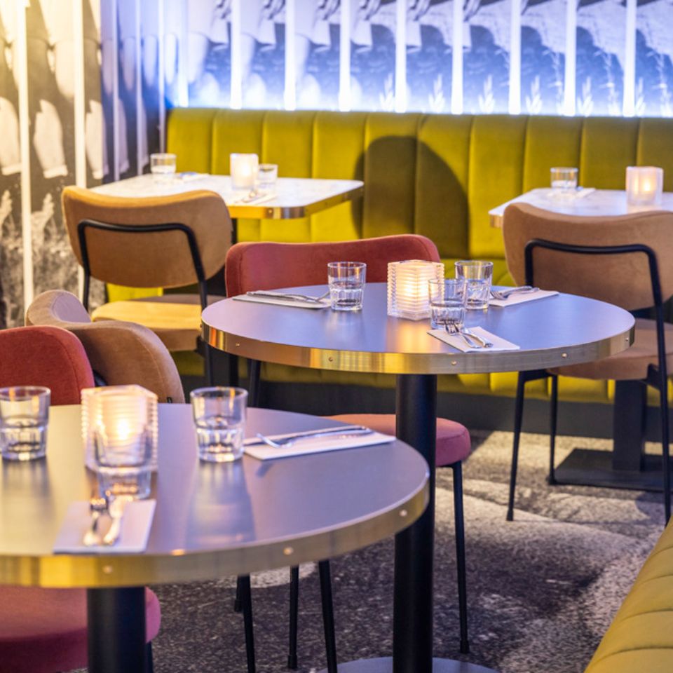 Laid tables in a restaurant with chairs and couches around it