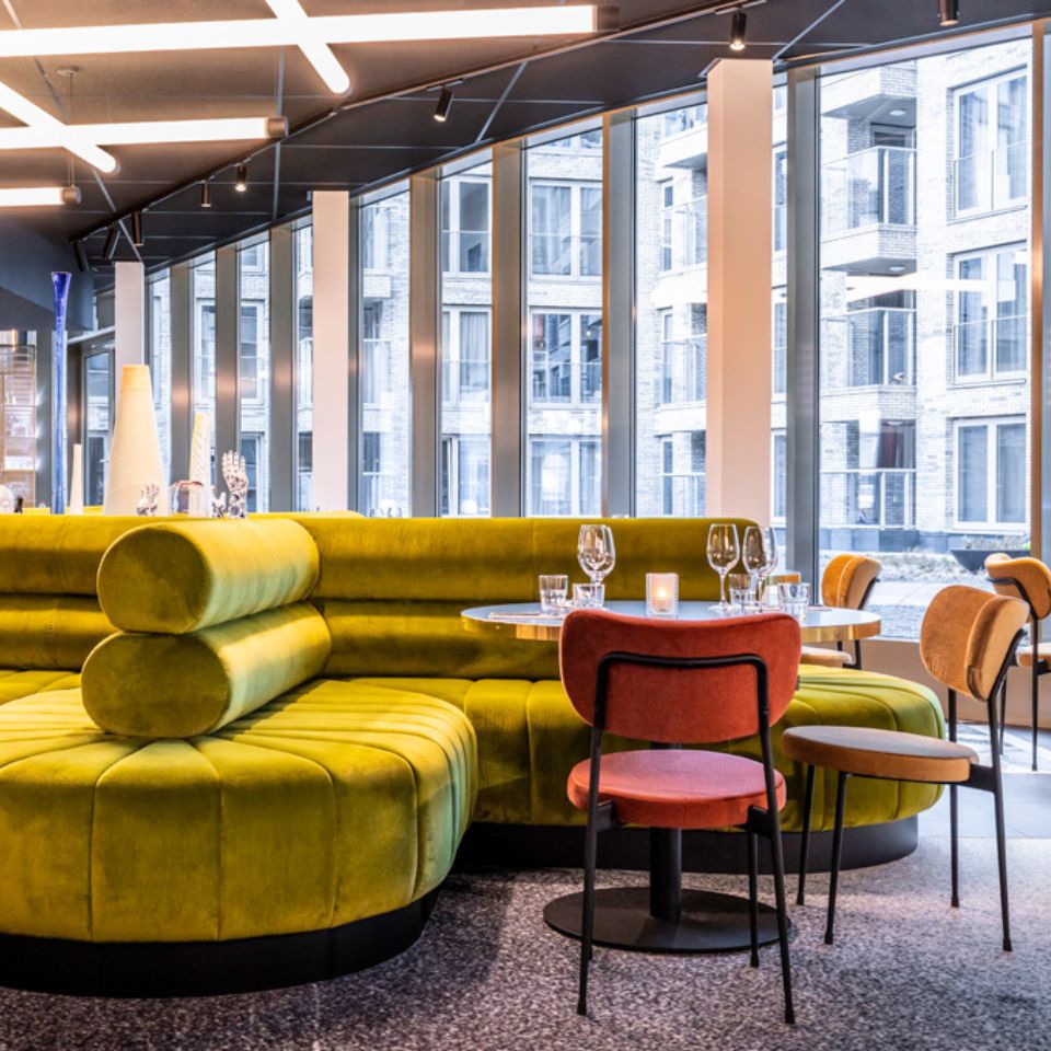 Green round couches and two chairs around a laid table