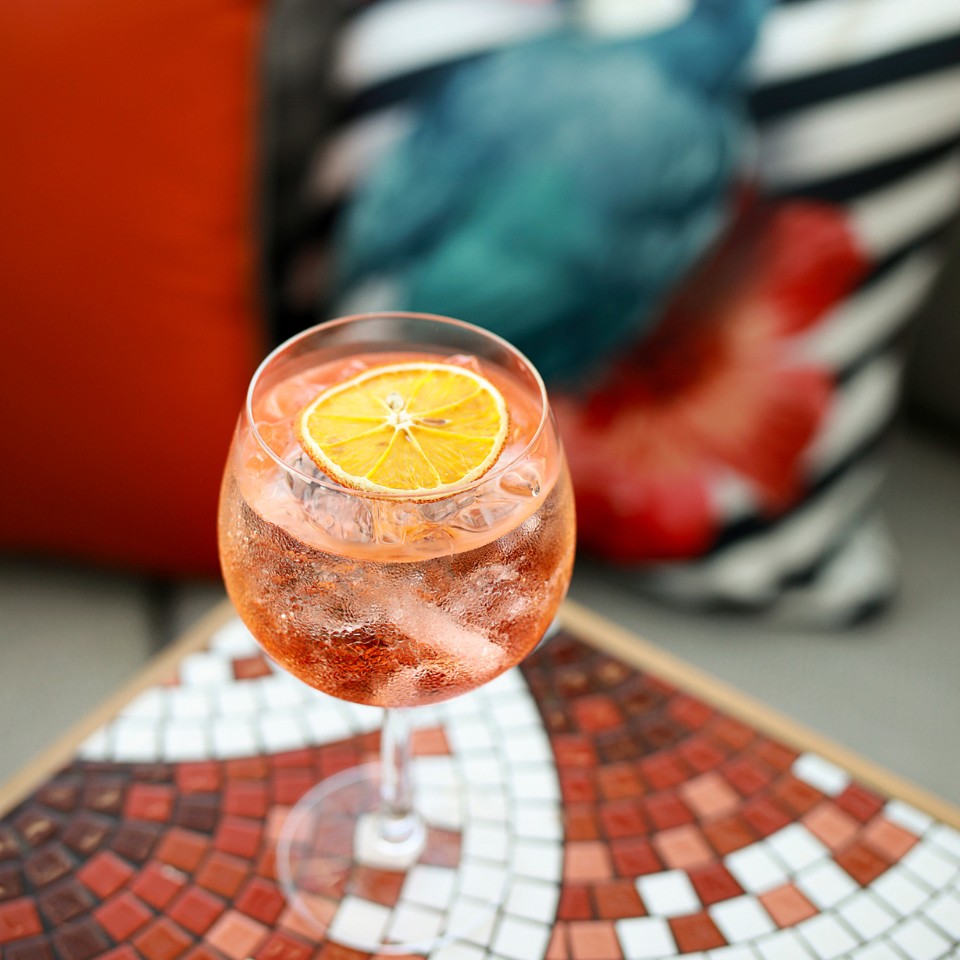 an orange drink with a dried orange slice servecd at a small table with colourful mosaic