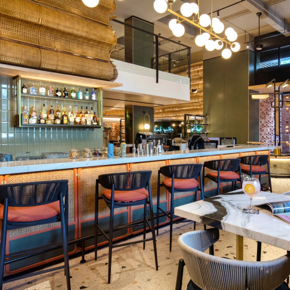 A bar with bar chairs in front of it, the bar is equipped with different liquors