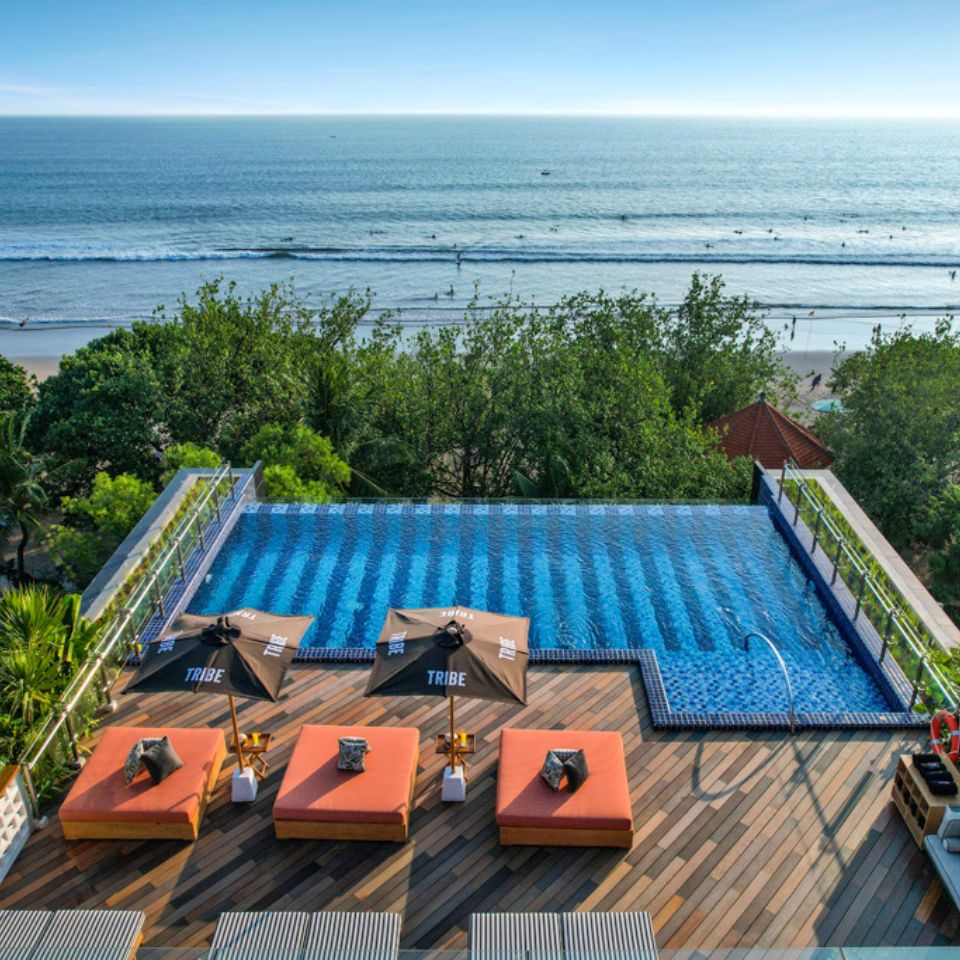 Bird's eye view of the rooftop pool with the beach in the background and orange lounge chairs