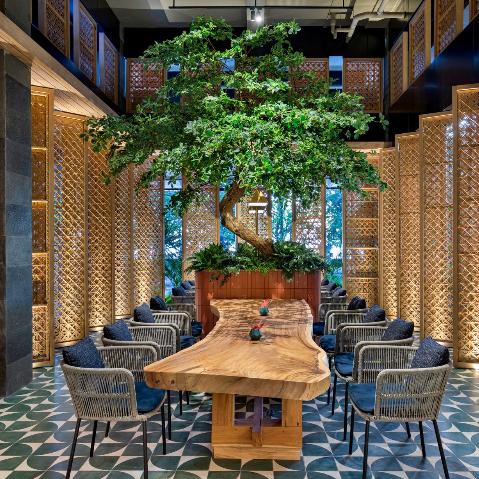 Large wooden tabe with chairs around it, an indoor tree as well as several room dividers