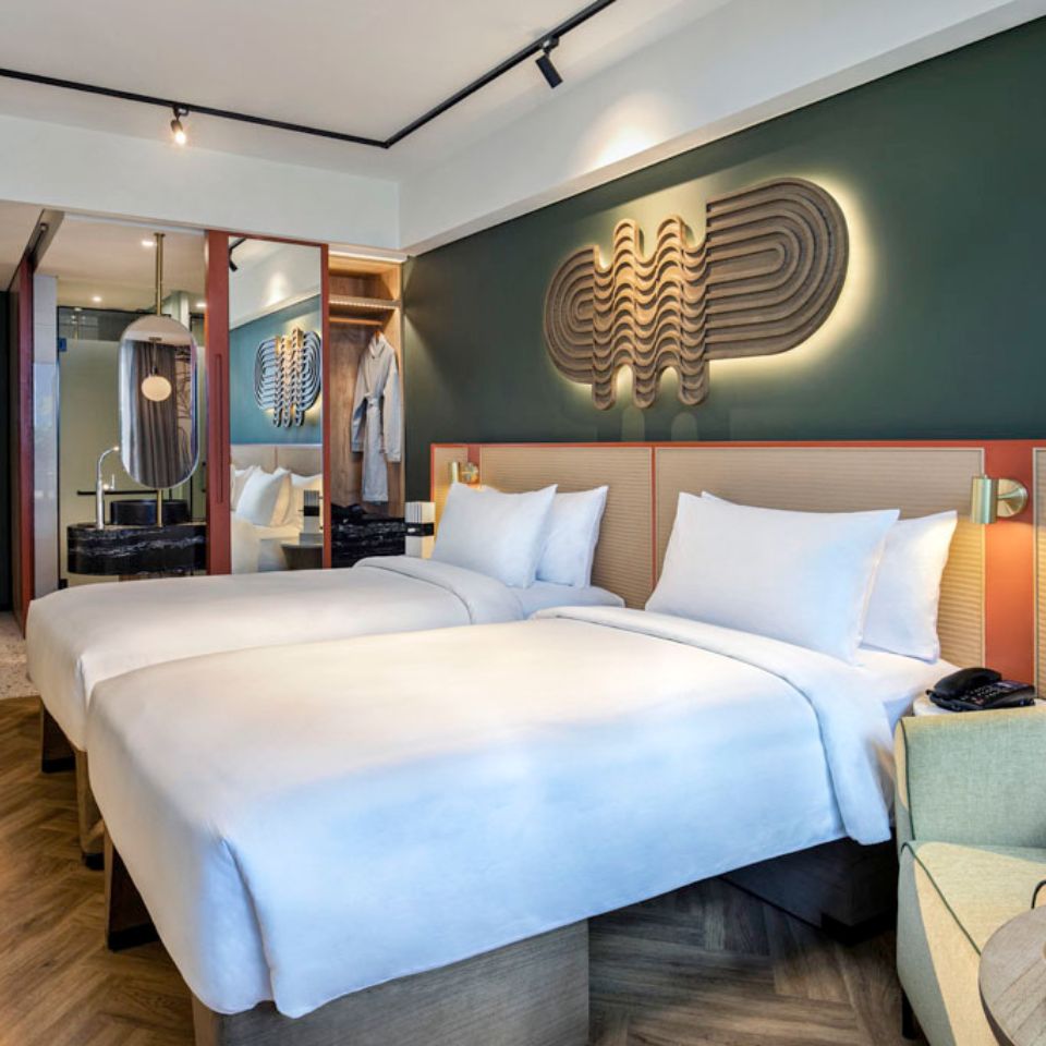 Twin beds in a hotel room with a wardrobe and a bathroom in the background