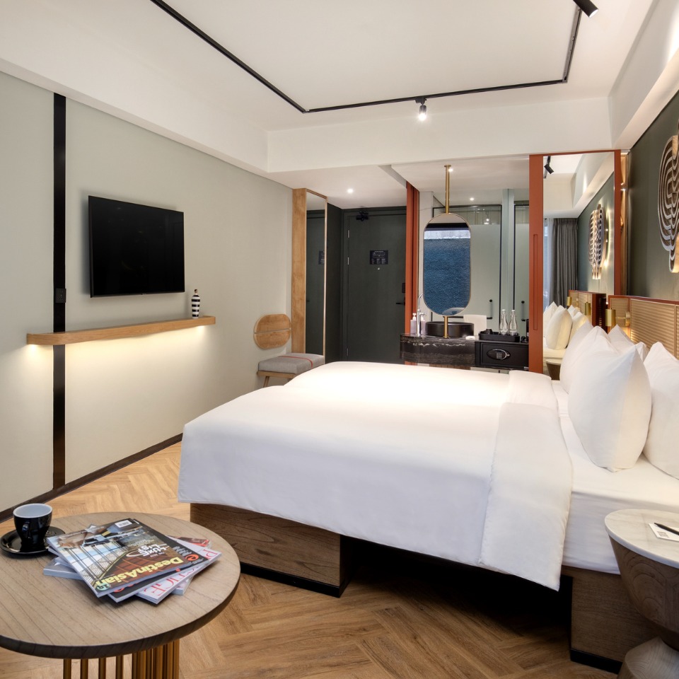 A guest room a double bed and a mirror, the open bathroom is visible