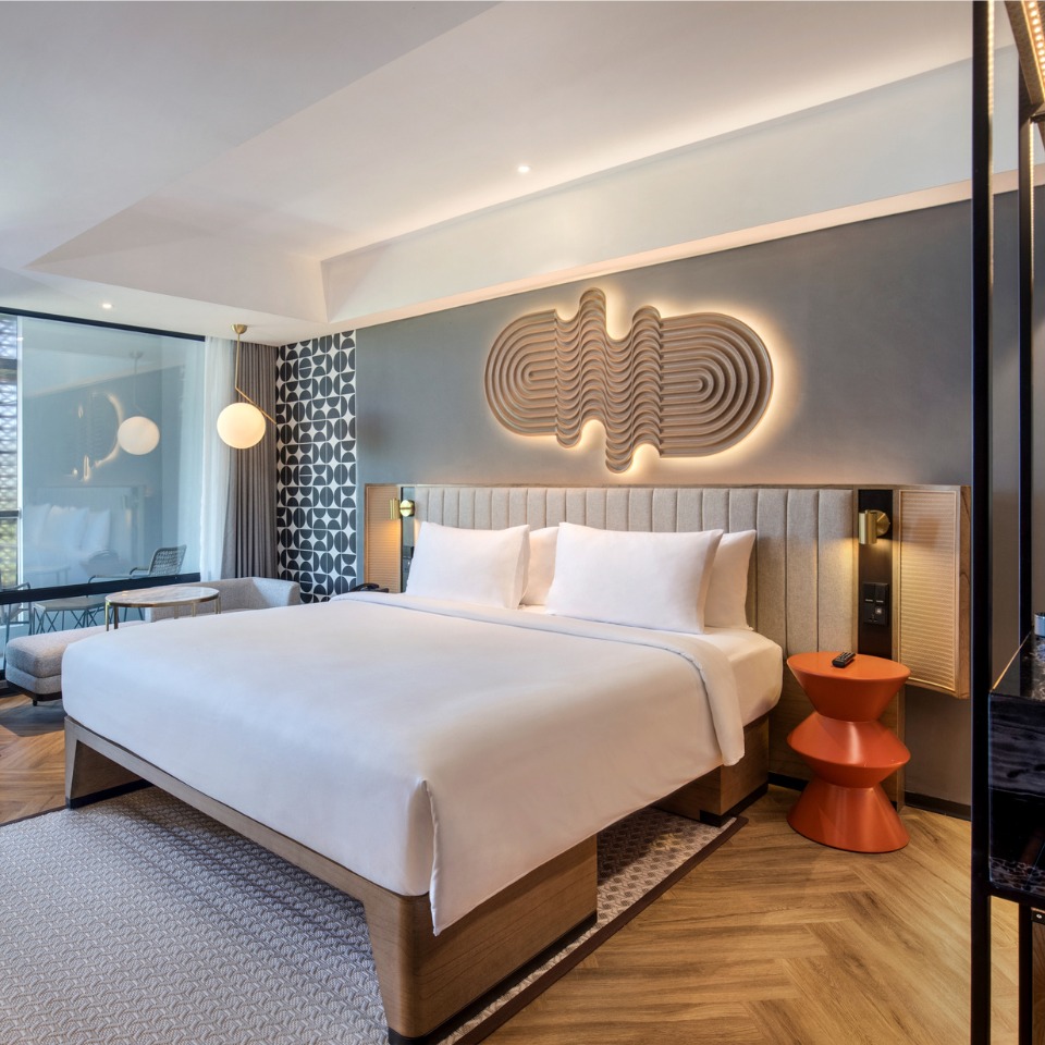 Double bed with white linens and a balcony in the background