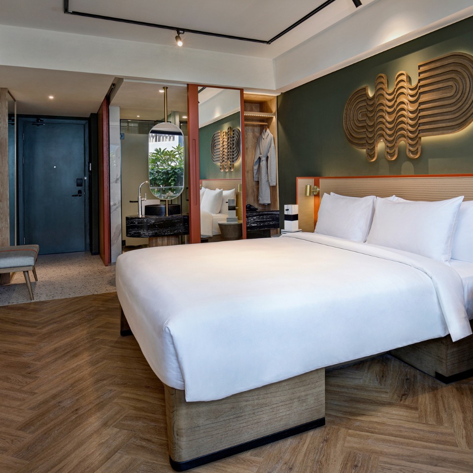 A guest room a double bed and a wardrobe with a mirror, the open bathroom is visible