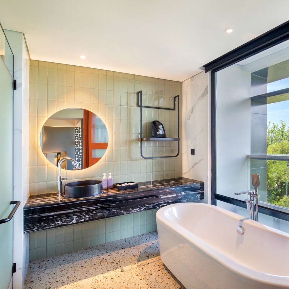 Bathroom with a bathtub and a round mirror