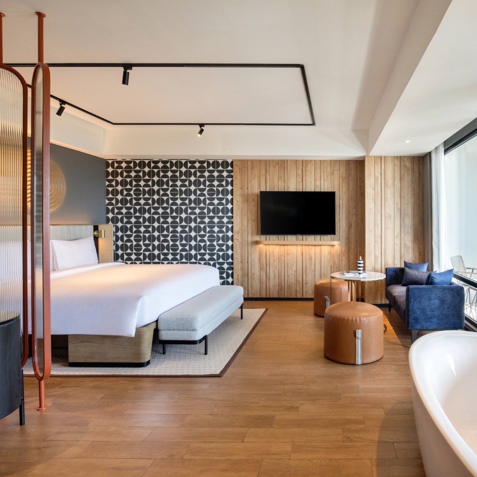 Suite at TRIBE Bali Kuta Beach with a double bed, and a TV, one of the walls is designed with eye-catching black and white symbols