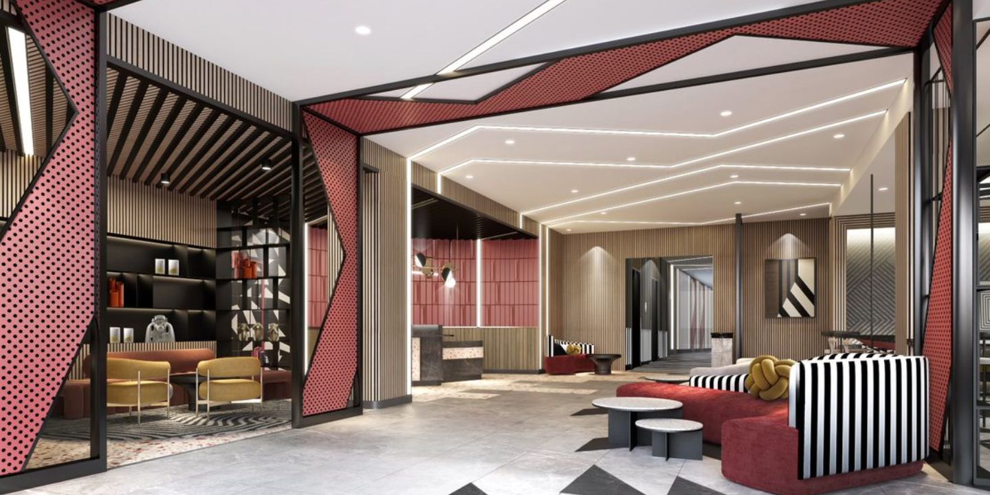 A modern hotel lobby with different seating options, mostly in muted red tones as well as bold black-and-white accents.