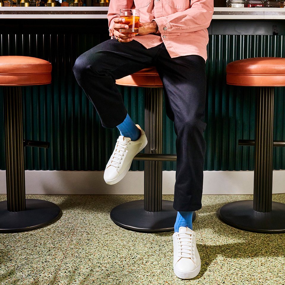 A person sitting on a bar, holding a drink.