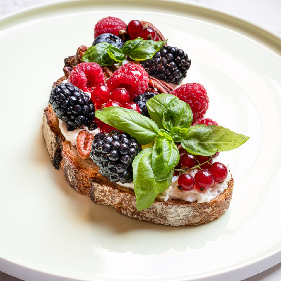a slice of bread, toppped with berries and basil