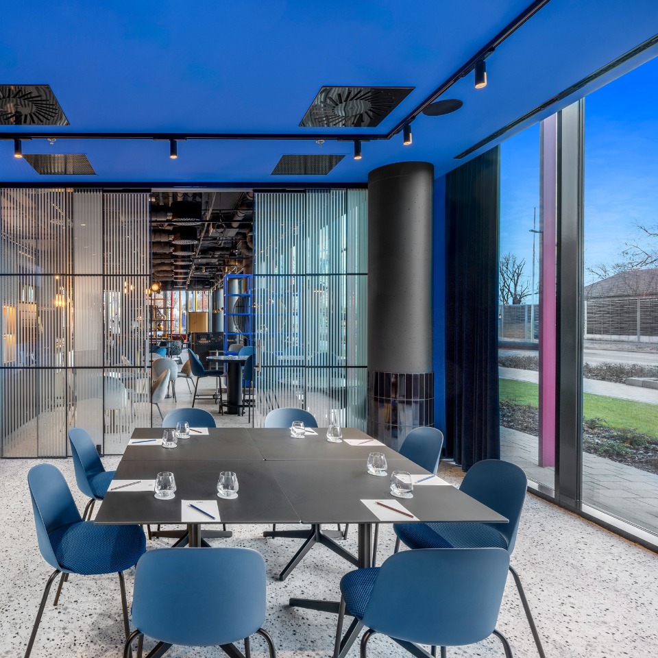 Meeting room featuring a blue ceiling, sleek tables and large windows with a view of the outdoors.
