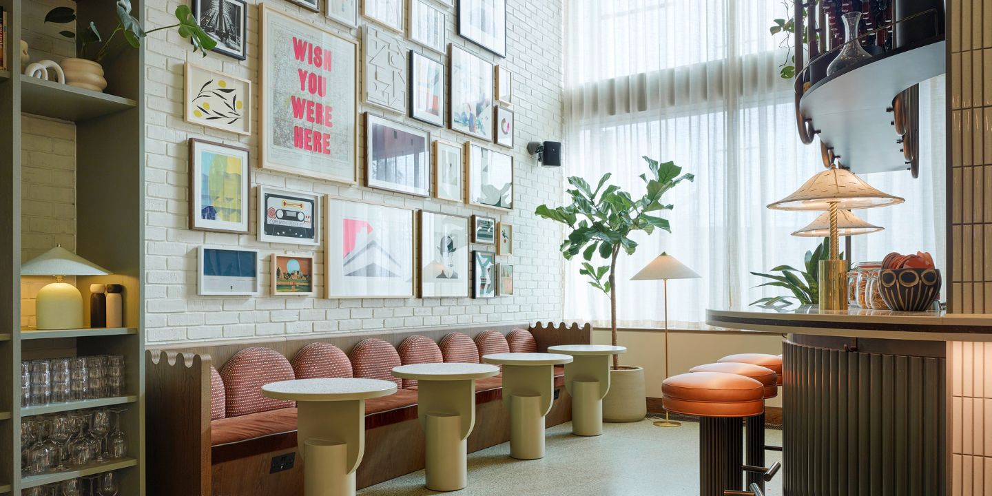 A large wall with framed pictures above couches and small tables