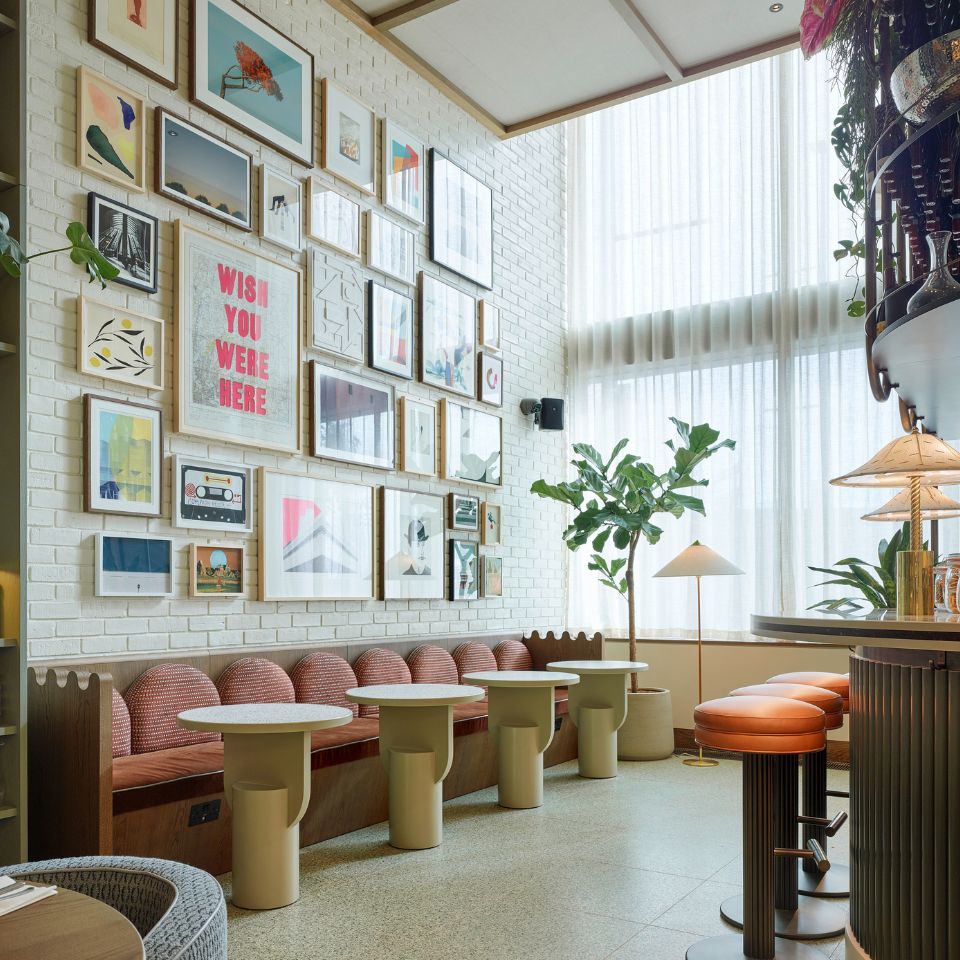 A large wall with framed pictures above couches and small tables