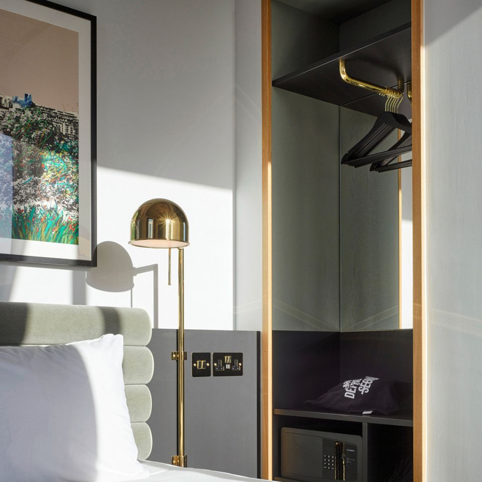 A double bed with framed pictures above it and a wardrobe next to it