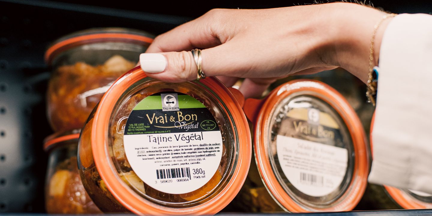 a hand grabbing a plastic container with vegetable tajine in it