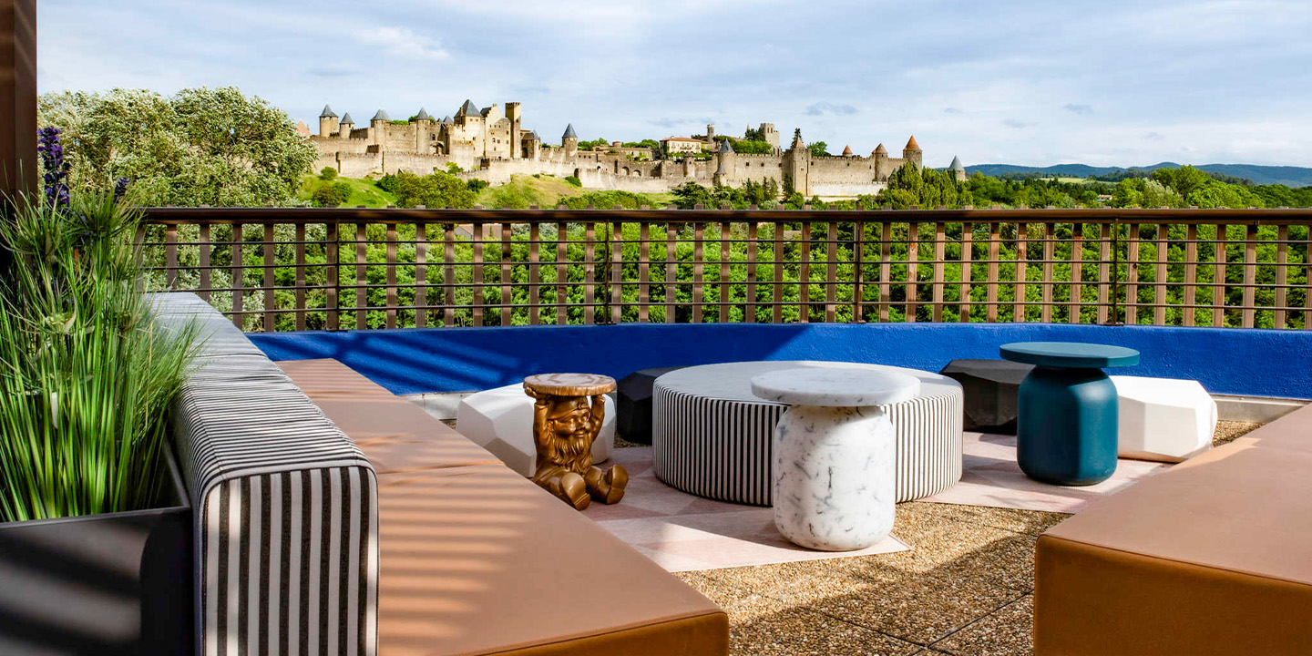 Outdoor sitting area with mismatched couches, small coffee table and spectacular view of a medieval city