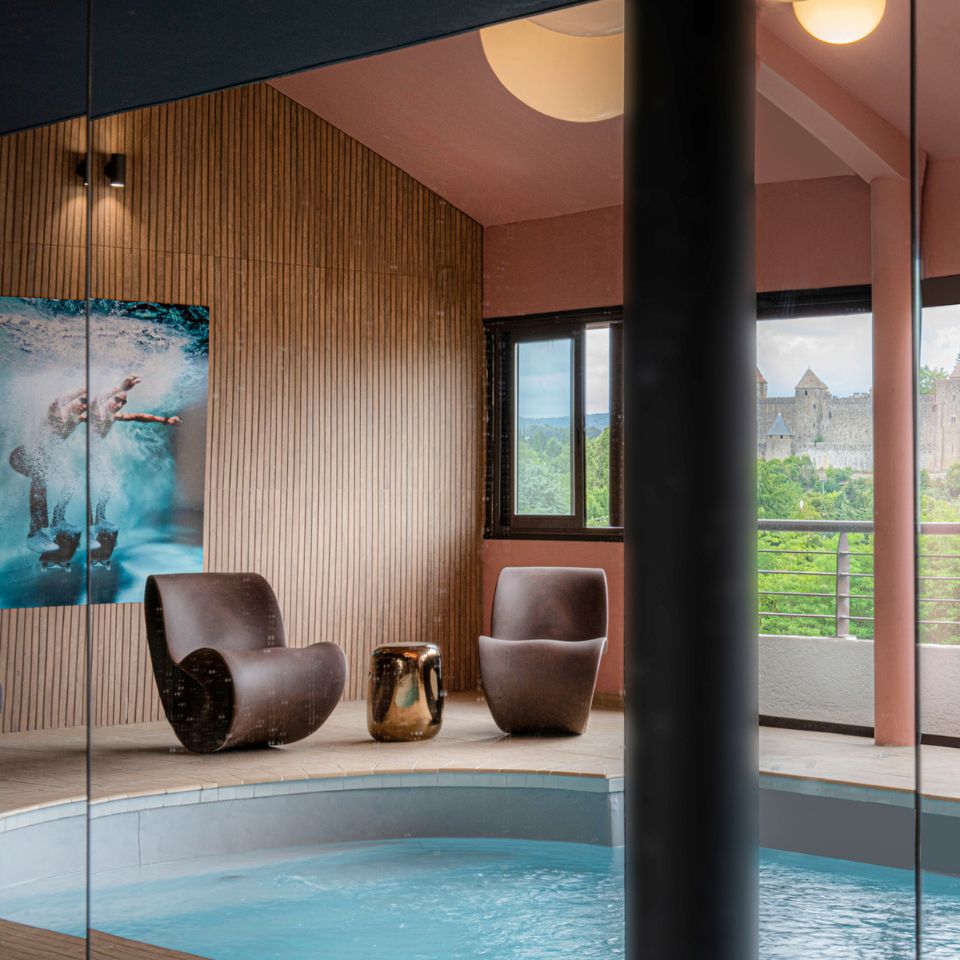 Small indoor pool with surrounding windows displaying view of a medieval city.