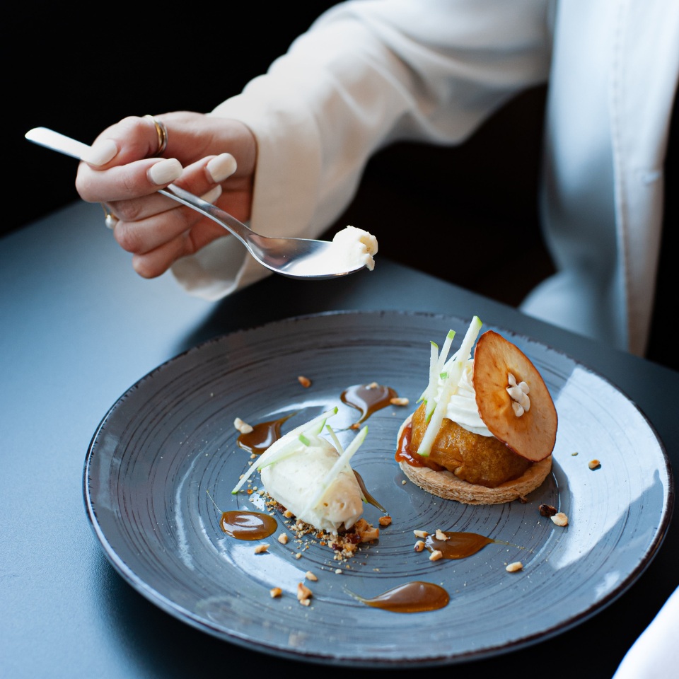 A dessert on a blue plate, a person is eating it with a spoon