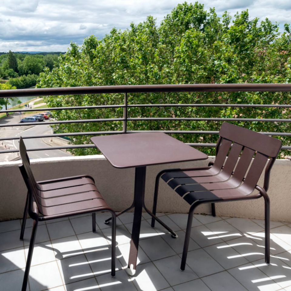 Balcony with two chairs and small table over with view over a medieval city