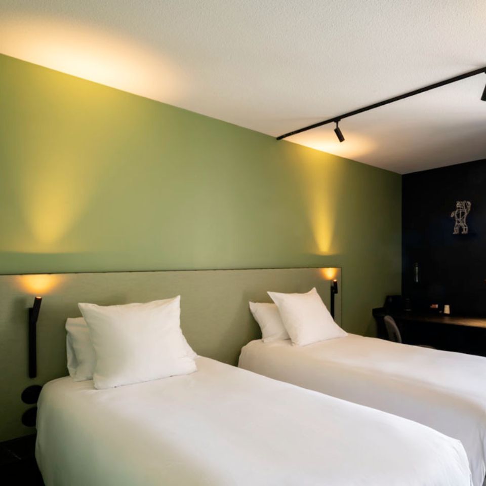 Two single beds next to one another against a light green wall