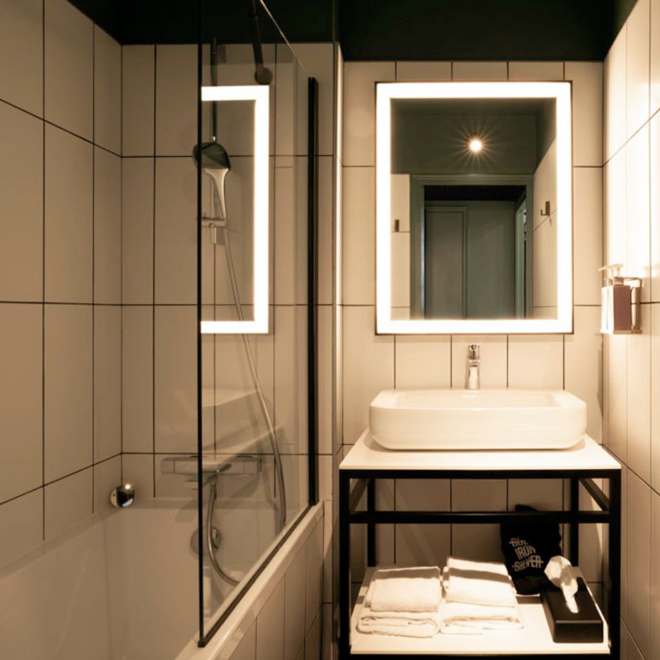 Bathroom with shower, bathtub, illuminating mirror, sink and folded towels