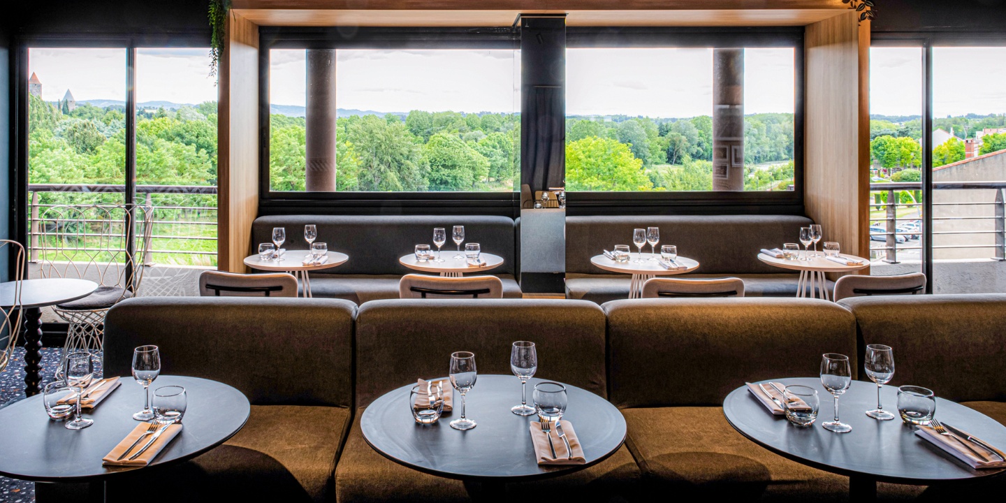 Restaurant dining area with small round tables and view of medieval city.