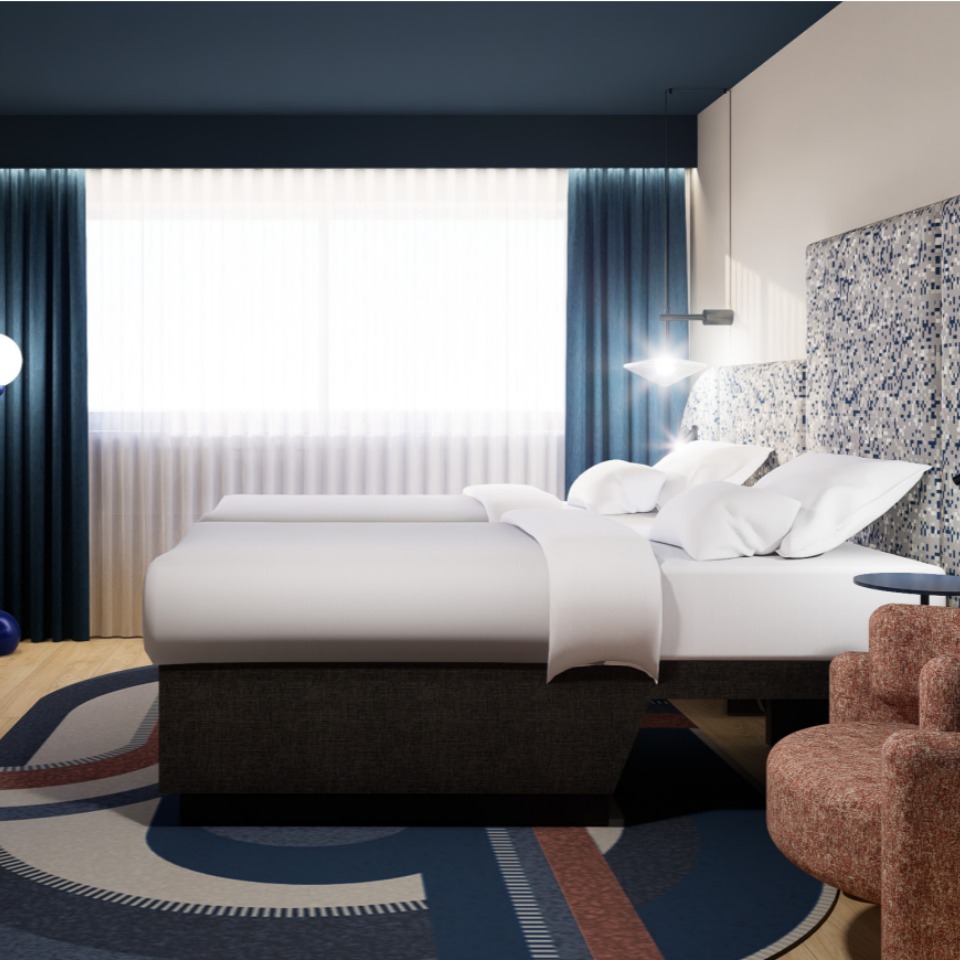 A hotel room featuring twin beds, a desk, a cozy chair, and a large window with sheer curtains, all in a contemporary style.