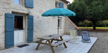 back patio with picnic table and blue umbrella