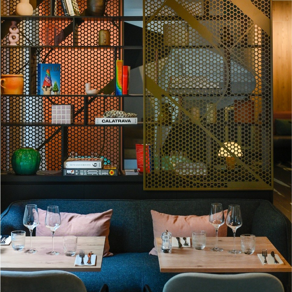 Modern restaurant interior featuring a stylish bookshelf, cozy seating, and elegantly set dining tables with glassware.