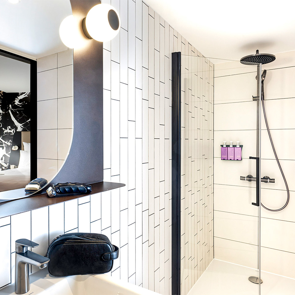 White tiled backroom with rain shower with bedroom reflected in make-up mirror