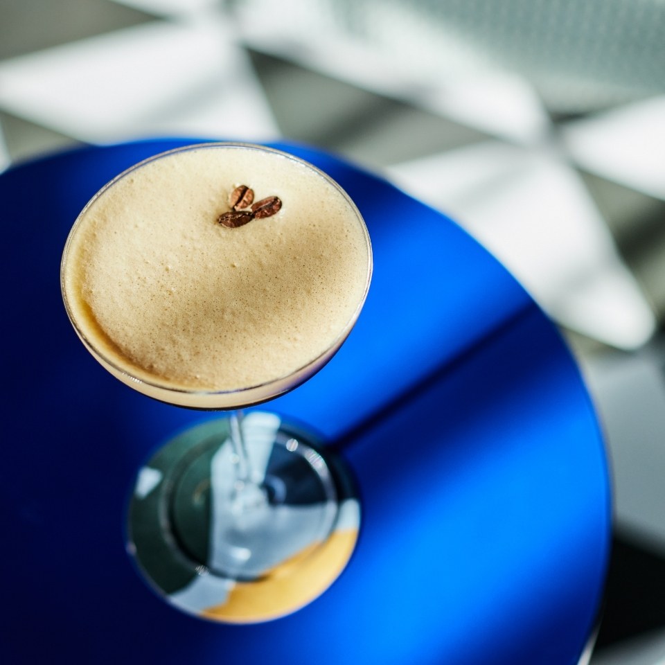 An espresso martini on a vibrant blue side table.