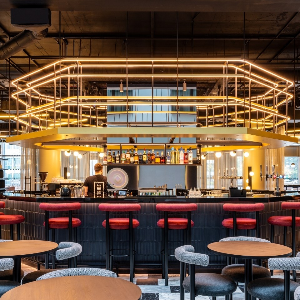 A modern bar with stylish seating, atmospheric lighting, and a bartender preparing drinks, in a contemporary lounge setting.
