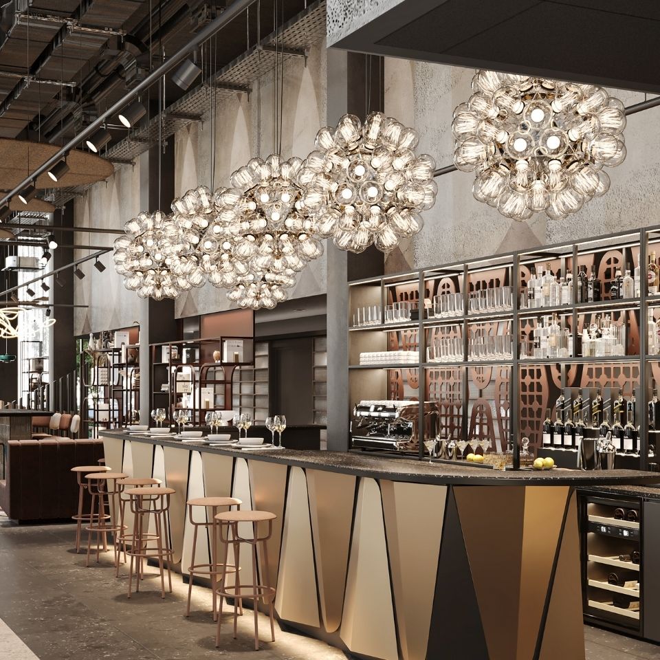 A stylish bar with elegant lighting, a sleek counter, and modern stools, showcasing an array of glassware and bottles behind the counter.