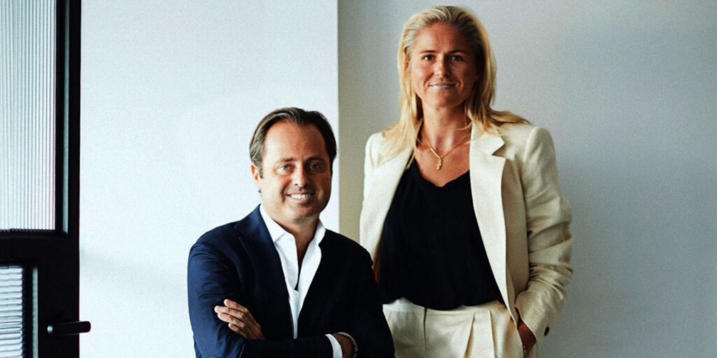 Melissa Peters is standing next to Marc, he is wearing a dark blue suit and she is waring a white suit