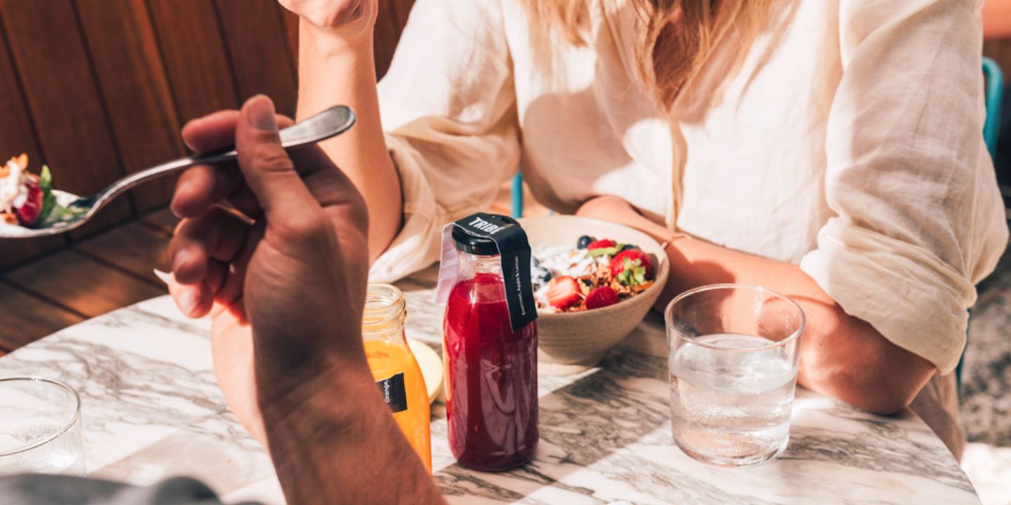 Two people eating breakfast and having juices in glass bottles