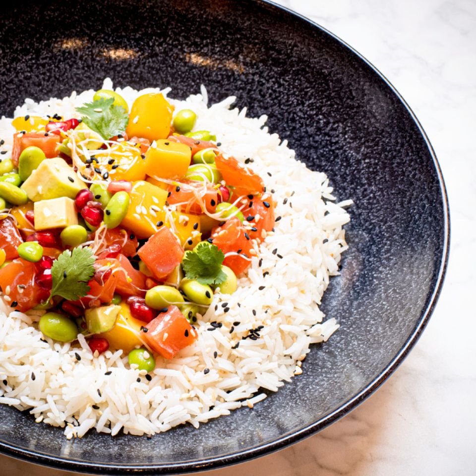 Rice with colourful vegetables being served in a black bowl