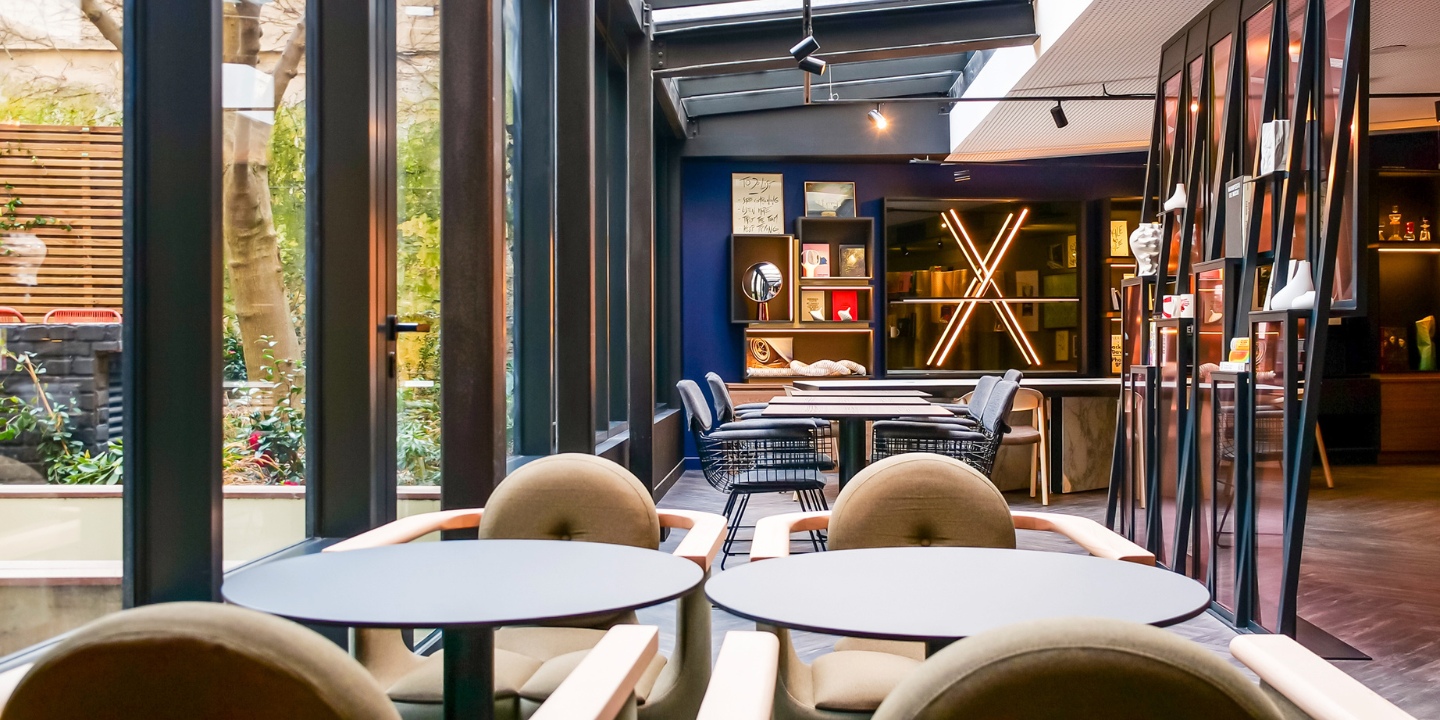 Several chairs and tables in a big room with large windows