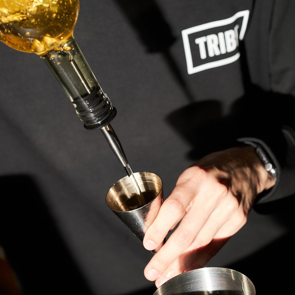 A barkeeper is pouring liquor into a jigger