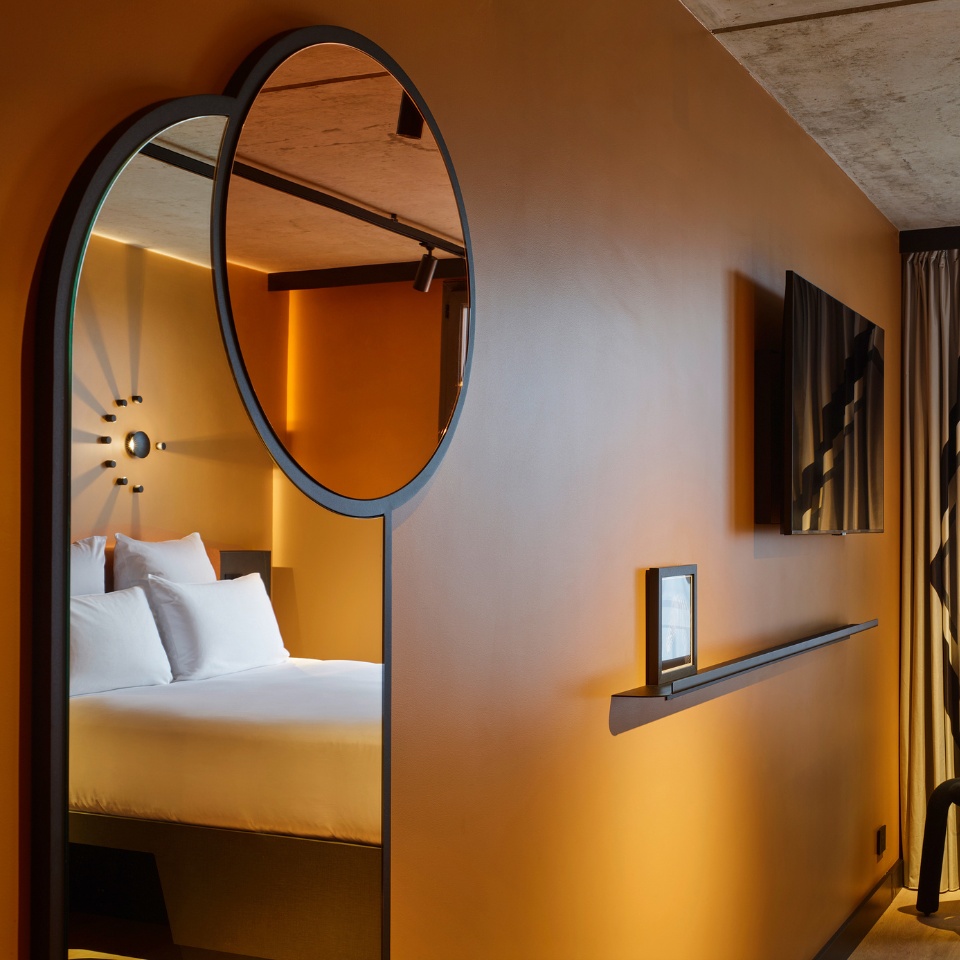A double bed in a large mirror on an orange wall
