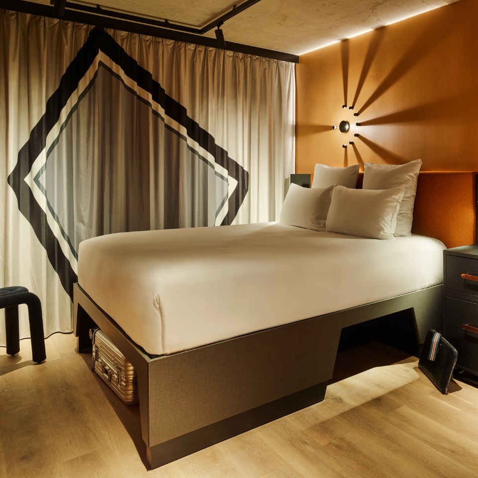 Guest Room with a double bed, small black desk and curtains, the walls are orange