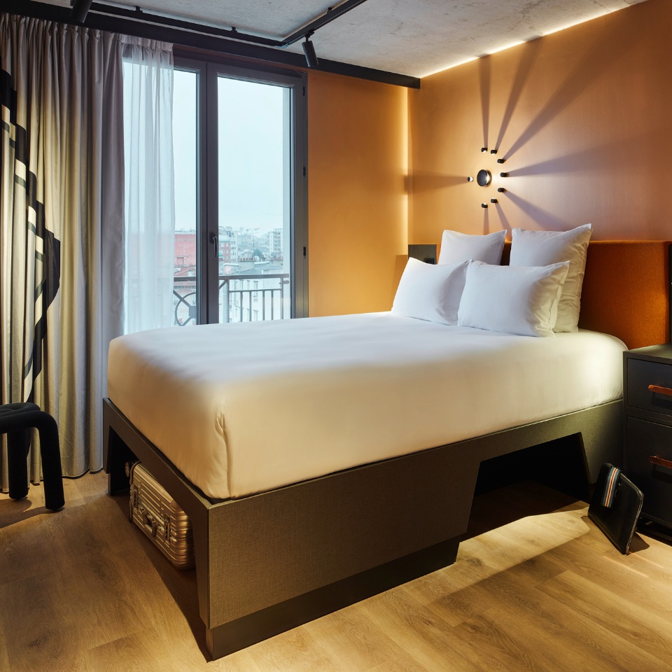 Guest Room with a double bed, small black desk and curtains, the walls are orange