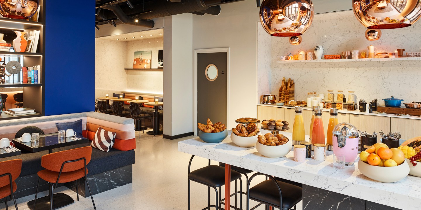 A breakfast buffet with several juices, baked goods and fruit on a marble counter