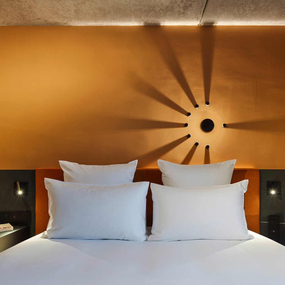 a double bed and an orange headboard against an orange wall