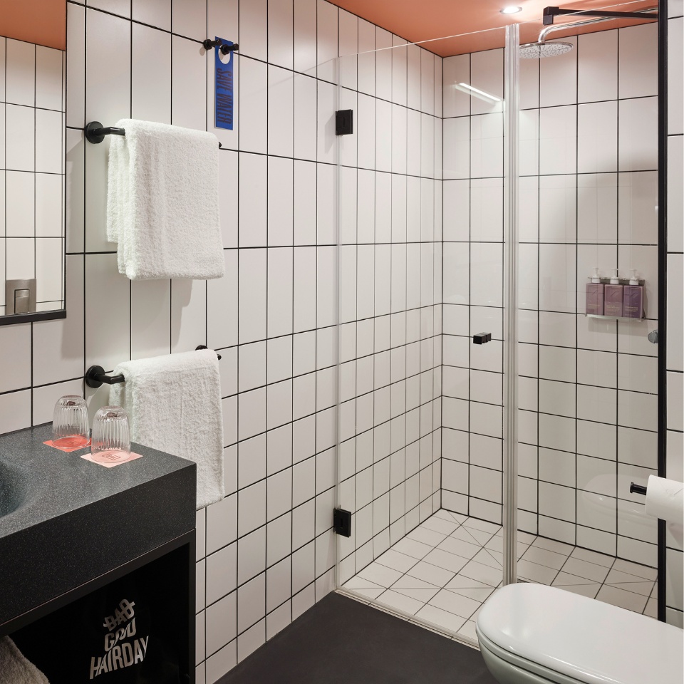Bathroom with a black sink, a white shower and white towels on the wall