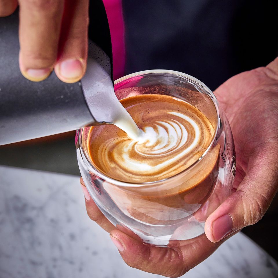 latte art made by a barista in a clear cup