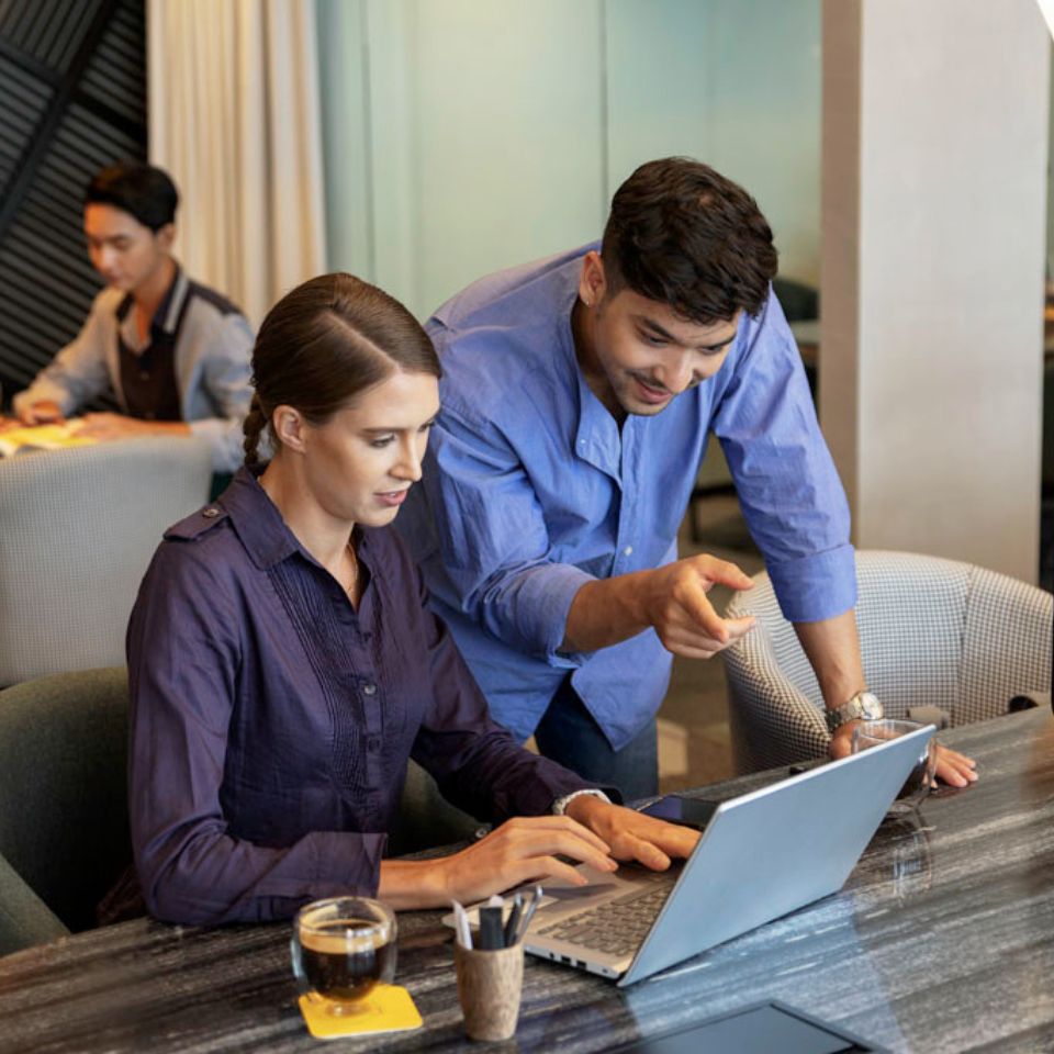 Two people looking at a laptop, engaging in conversation