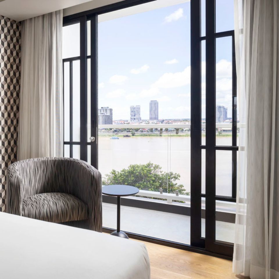 A grey armchair and a small black table next to it, in front of a floor to ceiling window